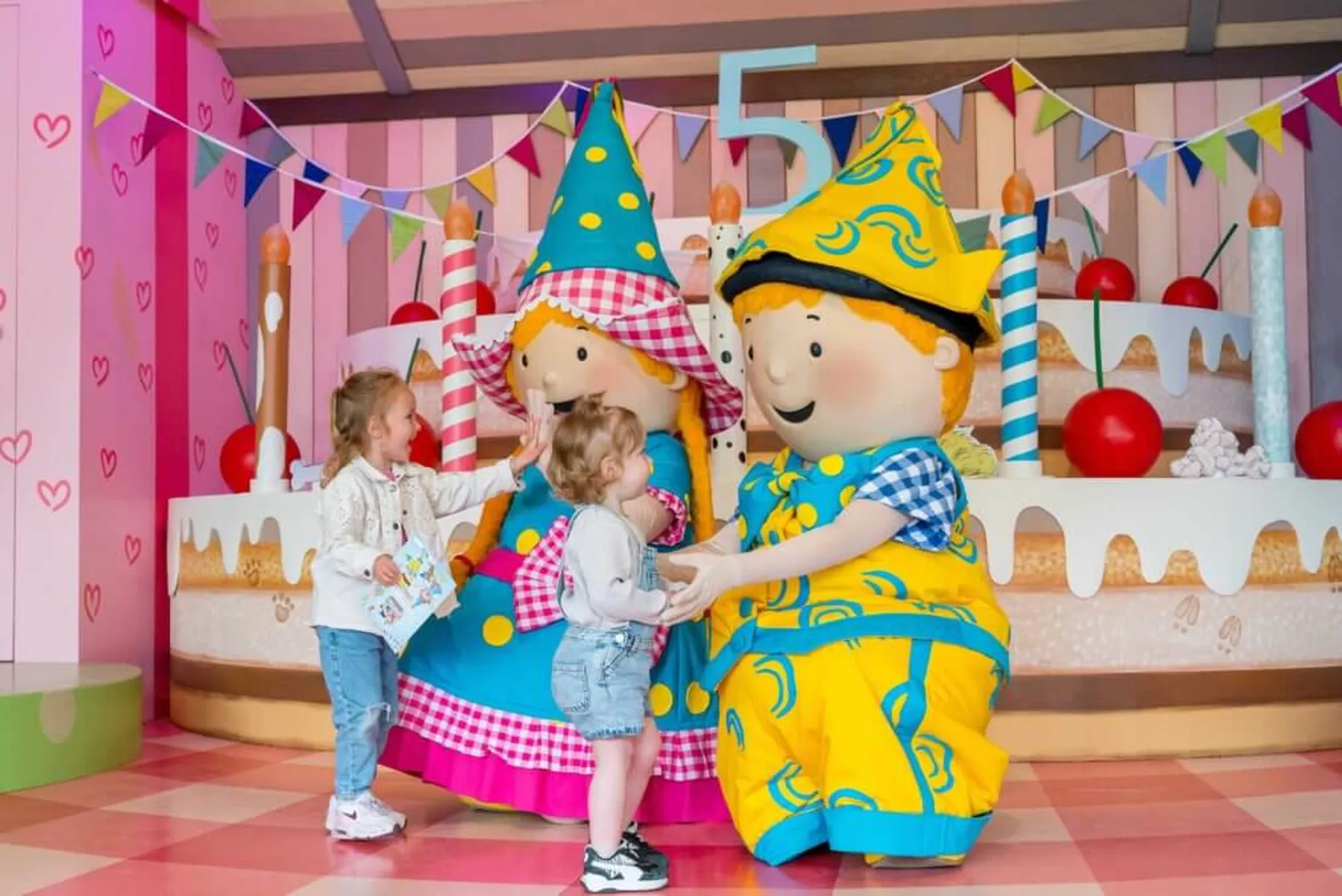 Kinderen begroeten mascottes in kleurrijke omgeving