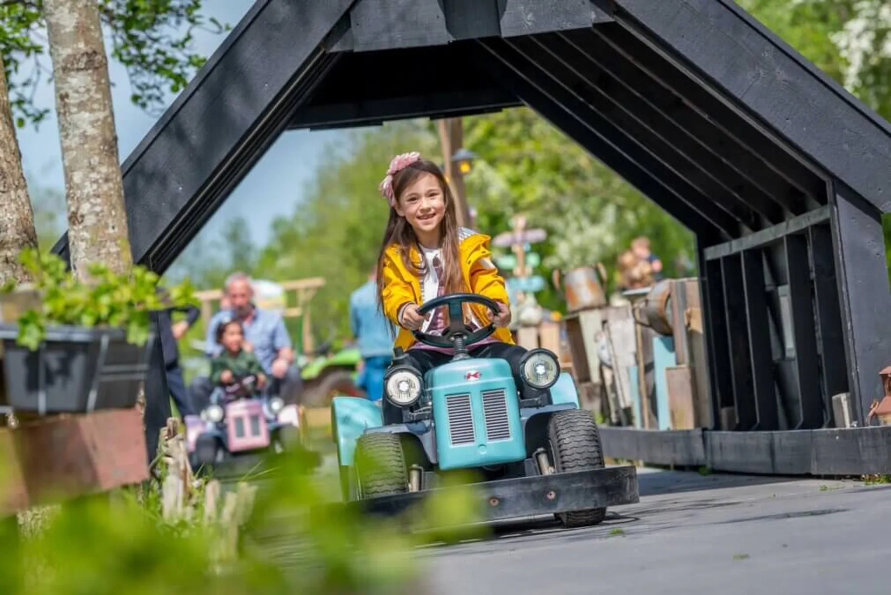 Lachend meisje rijdt op speelgoedtractor in Molenwaard