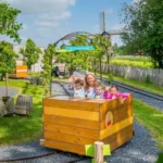 Moeder en kinderen genieten van een rit in houten karretje