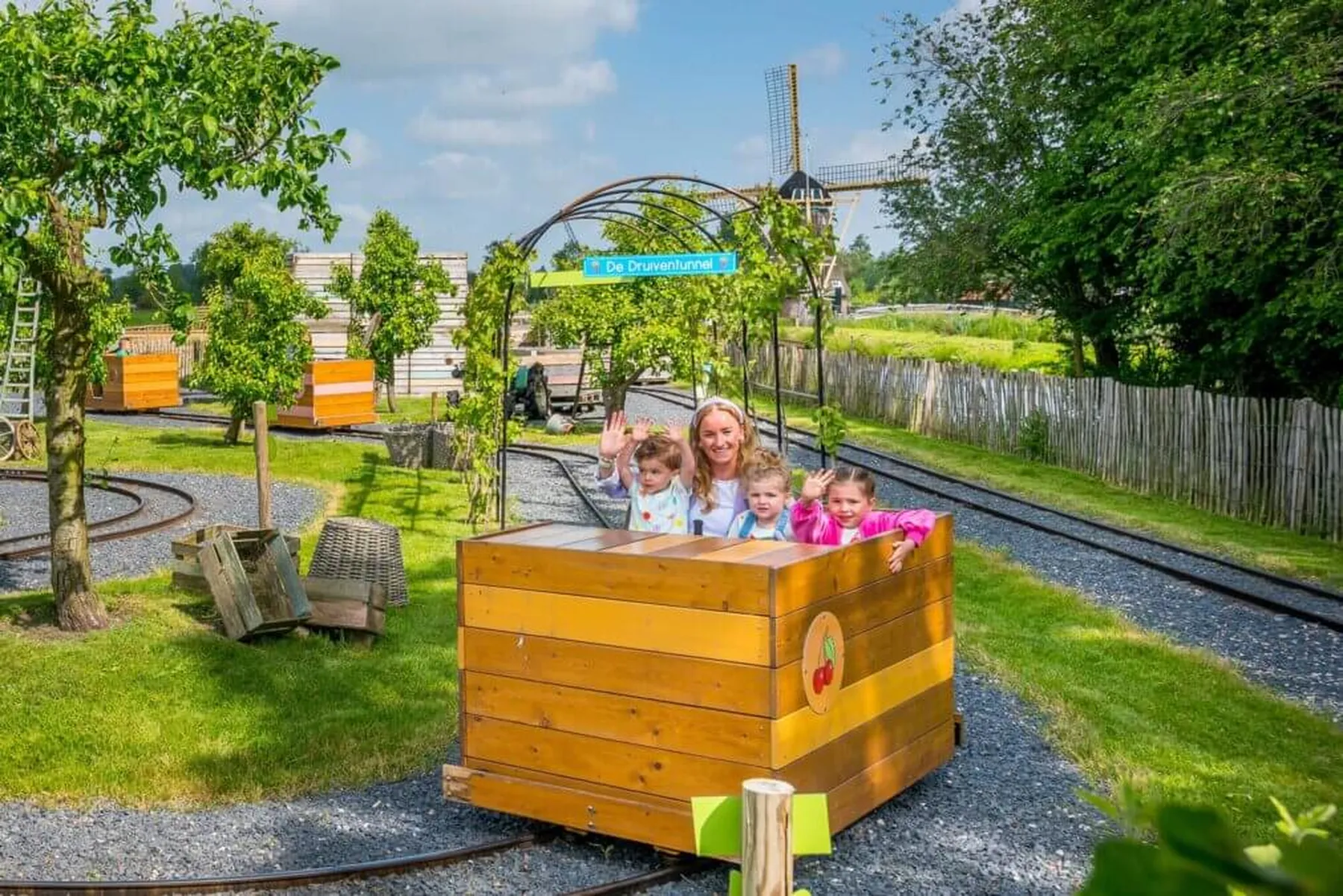 Moeder en kinderen genieten van een rit in houten karretje