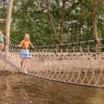 Kinderen steken een touwbrug over boven het water