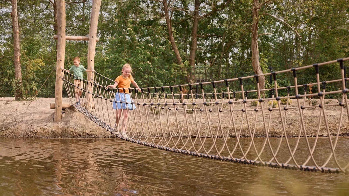 Kinderen steken een touwbrug over boven het water