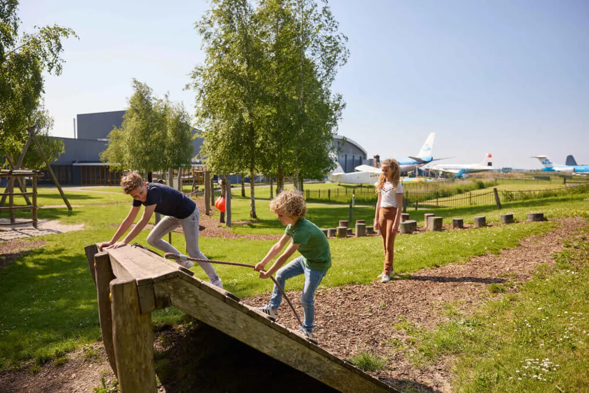 Kinderen spelen in de speeltuin met vliegtuigen op de achtergrond