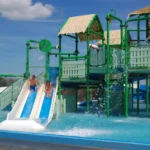 Kinderen glijden van de glijbanen in de Aquasplash op een zonnige dag