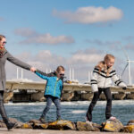 Moeder en kinderen wandelen langs de stormvloedkering van Deltapark Neeltje Jans