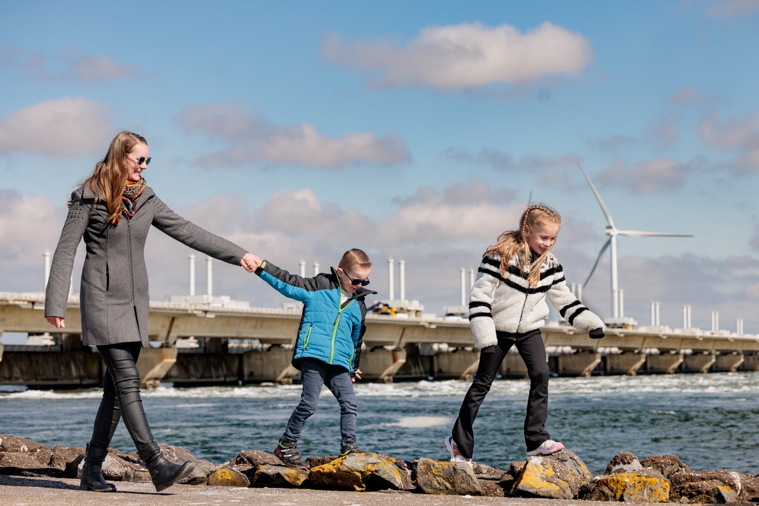 Moeder en kinderen wandelen langs de stormvloedkering van Deltapark Neeltje Jans