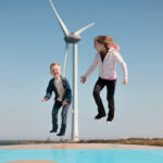 Kinderen springen op luchtkussen met windmolen op de achtergrond
