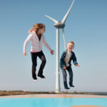 Kinderen springen op luchtkussen met windmolen op de achtergrond