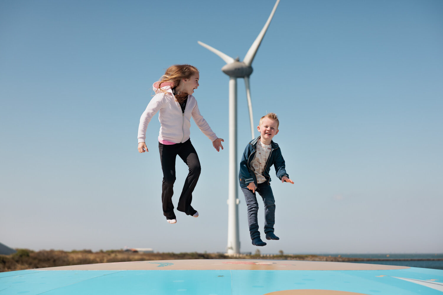 Kinderen springen op luchtkussen met windmolen op de achtergrond