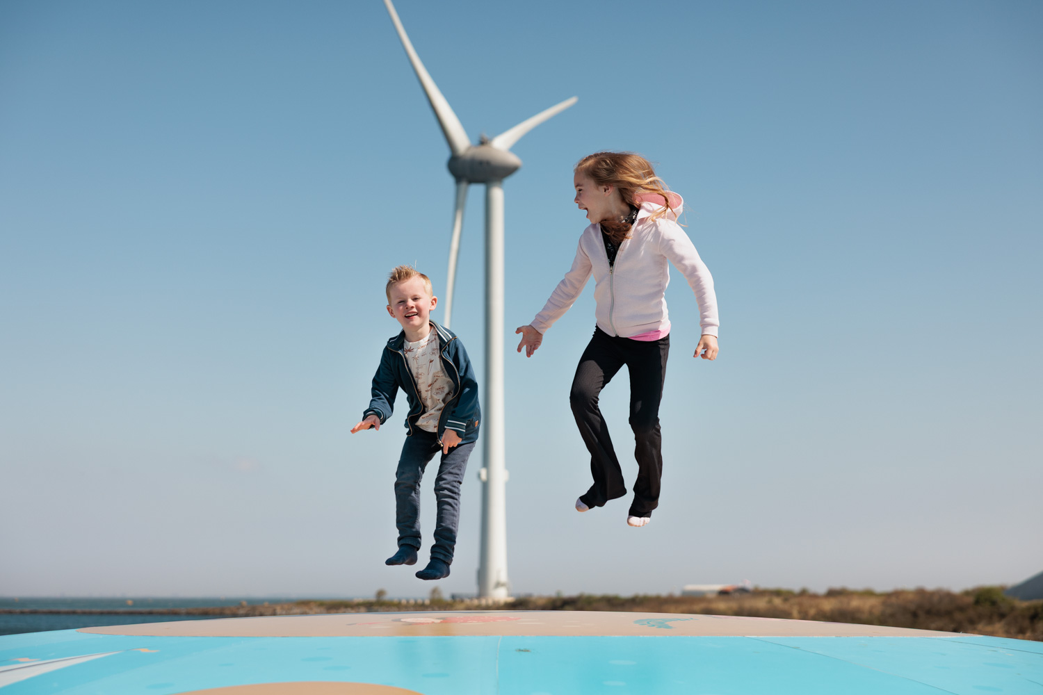 Kinderen springen op luchtkussen met windmolen op de achtergrond