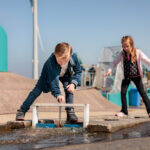 Kinderen experimenteren met waterstromen bij de waterspeelplaats