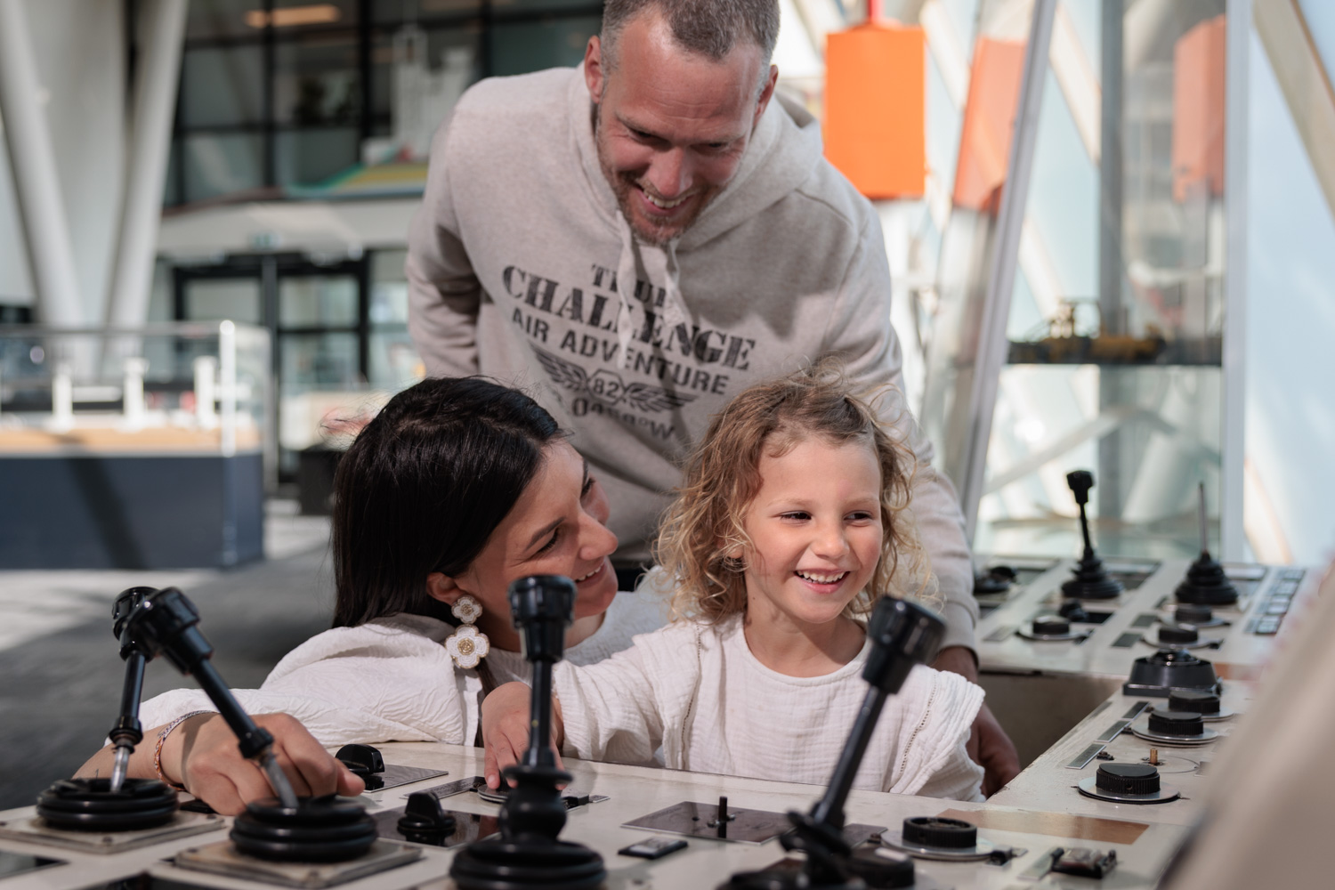 Lachend gezin bedient samen interactieve panelen met hendels en knoppen in een educatieve tentoonstelling over waterbeheer.