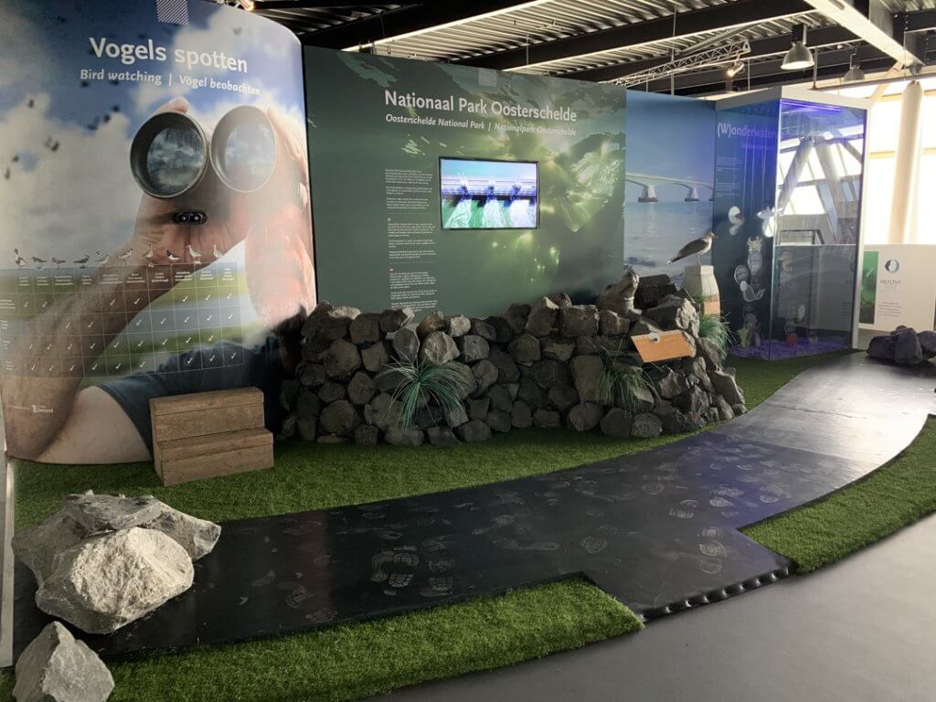 Educatieve binnenexpositie over Nationaal Park Oosterschelde bij Deltapark Neeltje Jans, met vogelspotwand, informatiepanelen, rotsen en een looproute.